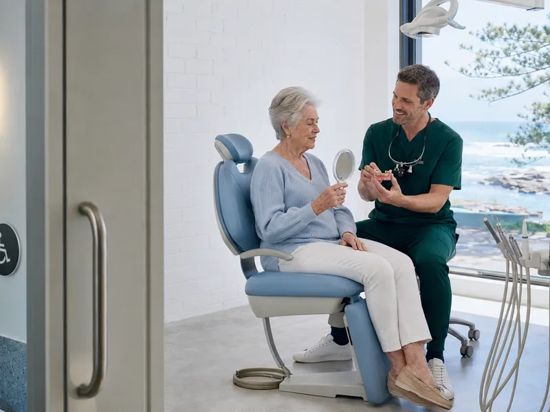 Patient admiring her smile in a mirror with her dentist