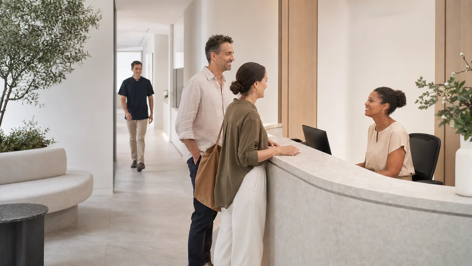 Patients at a dental practice reception with a clinician in the treatment corridor