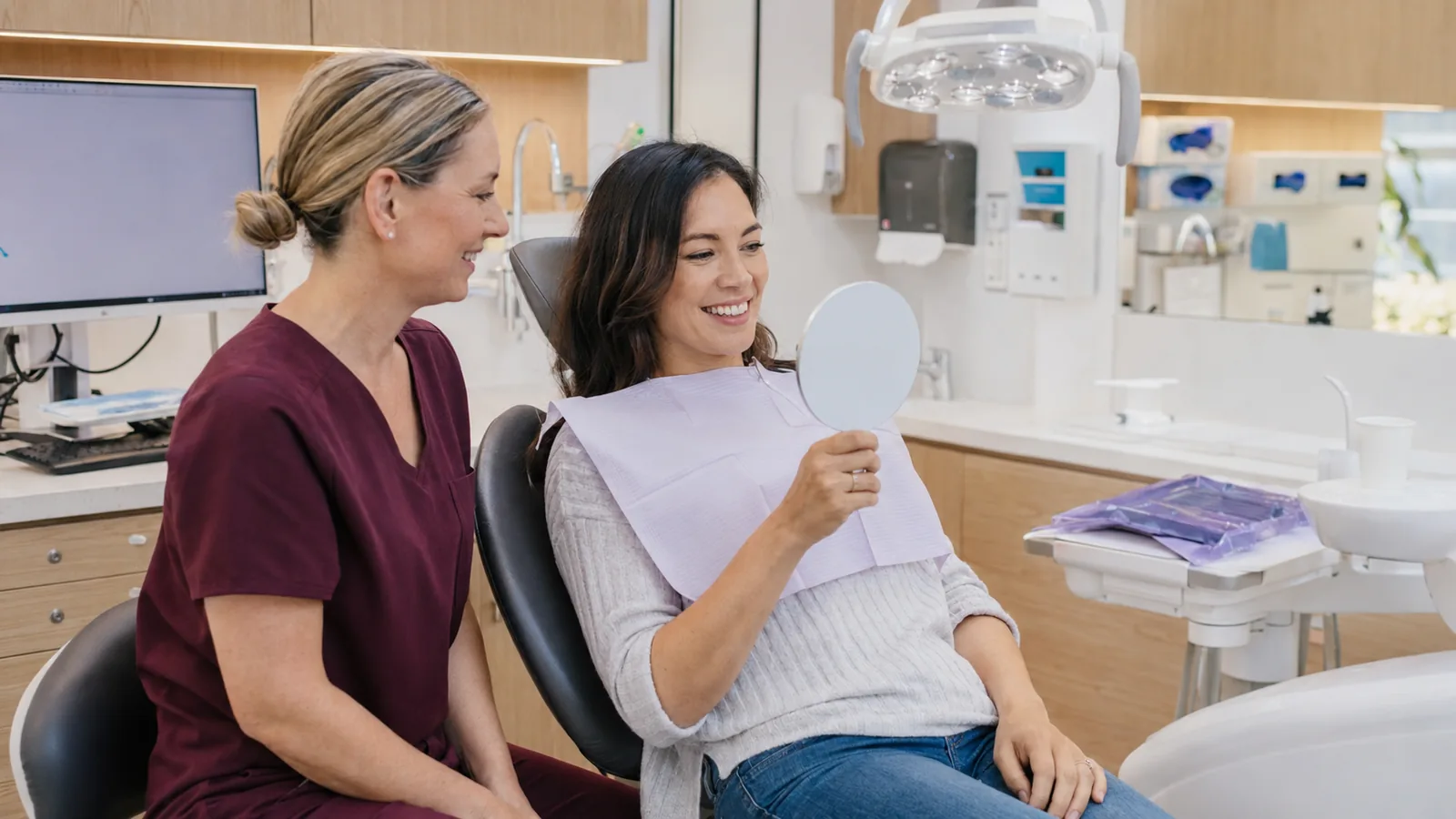 Patient reviewing her smile in a hand mirror with her dentist after treatment